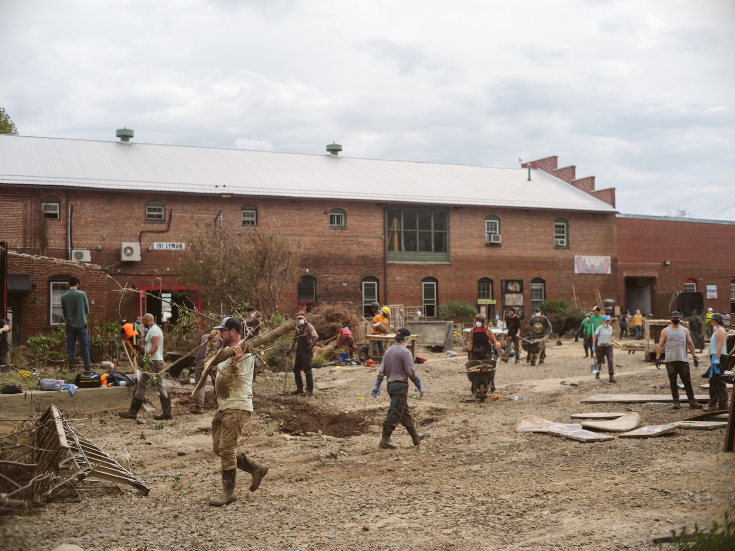 Asheville, North Carolina, USA — October 4th, 2024: Volunteers help clear debris from Hurricane Helene and salvage art outside Riverview Station in the River Arts District.