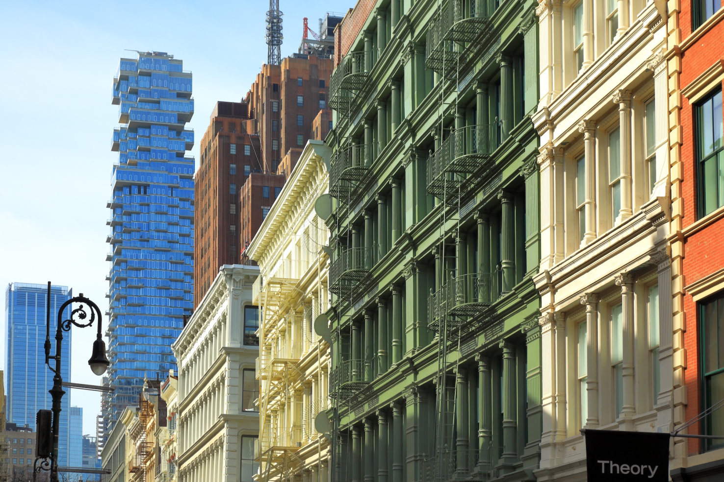 HIstoric colorful SoHo buildings in New York City with modern glass skyscraper in background.