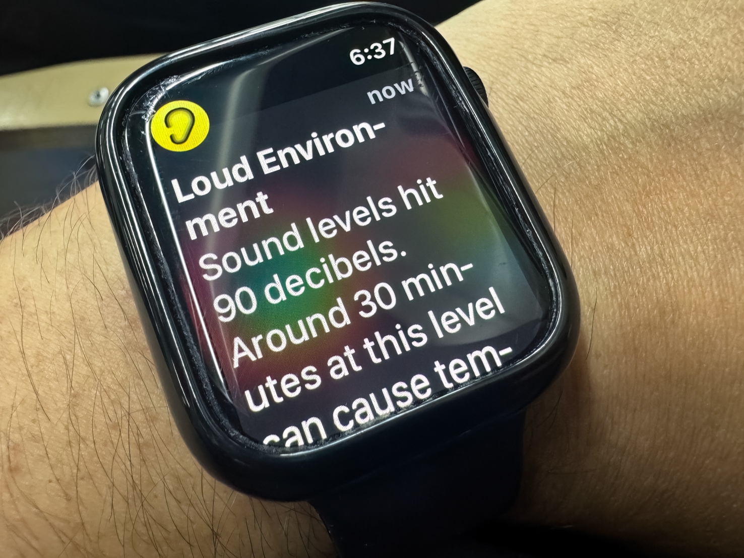 A person's Apple Watch reads "Loud environment: sound levels hit 90 decibels"