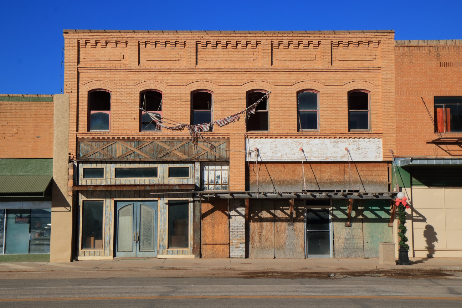 Vacant storefronts in a red brick two-story building in a small town in West Texas.