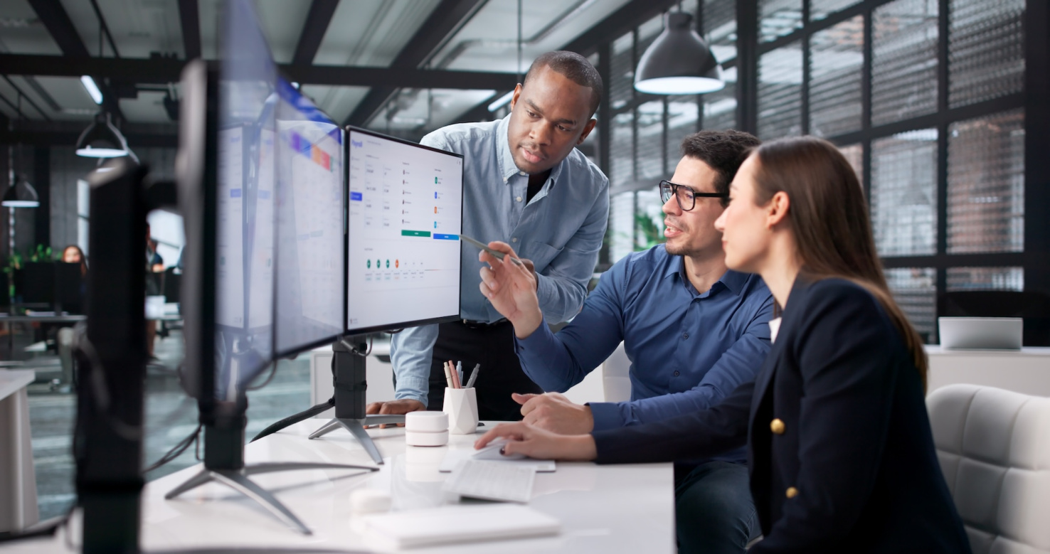Three people in office looking at a computer screen.