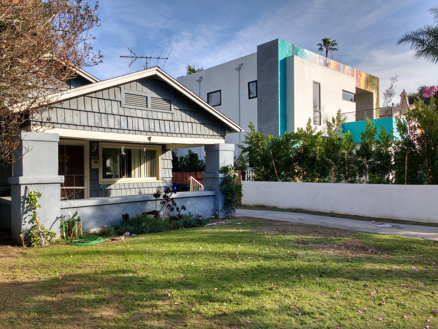Small older Craftsman-style home next to modern apartment building in Los Angeles.