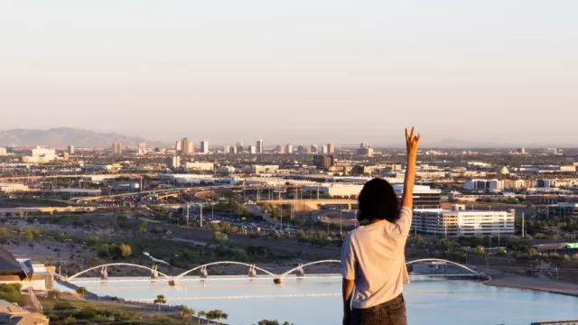 Arizona State University Master of Urban and Environmental Planning primary imager with a somen pointing to the sky and you see the city and river in the distance.