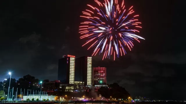 Nighttime view of tall buildings with red fireworks going off in a distance