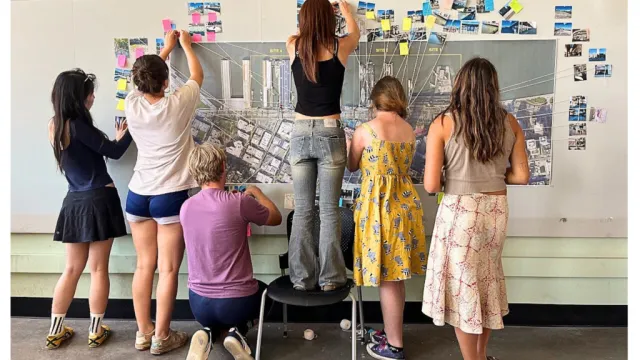 Group of students in a classroom posting colored postits up on the wall for a group excersize