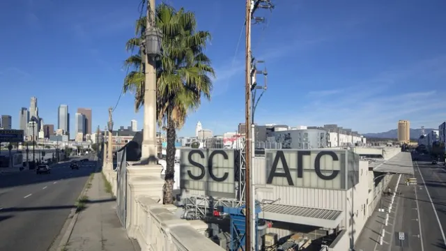 Image of a corner building with SCI_Arc with a palm tree in the background showing buildings in the background