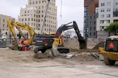 Yellow electric excavator digging at construction site in Los Angeles, California.