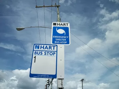 Close-up of HART bus stop sign for Route 1 and hurricane evacuation route sign on street pole in Tampa, Florida.