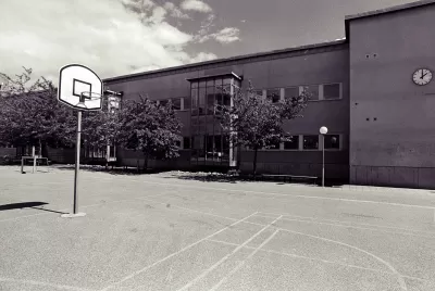 Low-saturation image of a concrete schoolyard with basketball hoop