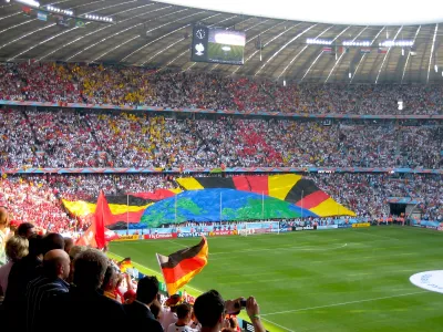 Soccer stadium in Berlin during 2006 World Cup full of fans waving German flags and a banner showing earth and radiant rays formed by bottom section of crowd.
