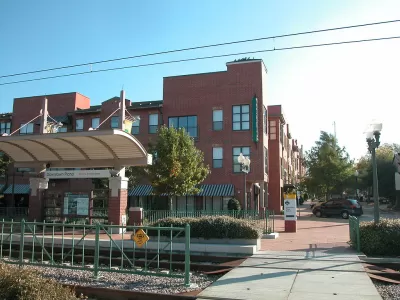 Above-ground downtown Plano train stop in front of red brick multifamily housing building.