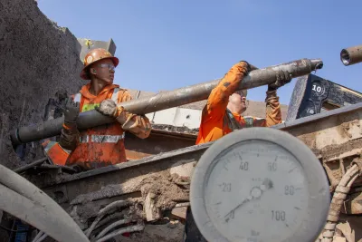 Worker in orange safety jacket working on California high-speed rail infrastructure.