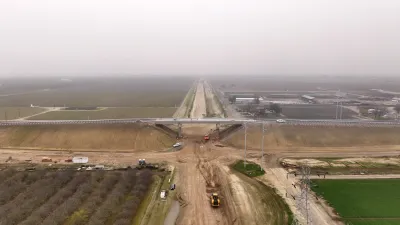Construction for California's high-speed rail line. A concrete bridge stretches over a dirt field. 
