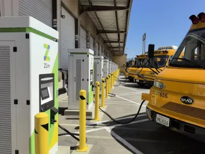 A row of school buses plugged into the power grid.