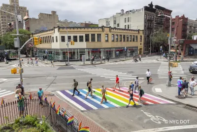 Pedestrians crossing a rainbow painted crosswalk in New York City.