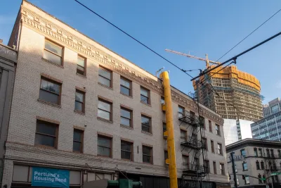 Brick building with high-rise under construction with yellow crane in background in downtown Portland, Oregon.