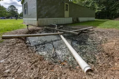Mobile home with pipe directed into the yard into a pit of standing sewage.