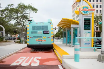 Light teal SunRunner transit bus in St. Petersburg, Florida parked at station on red painted bus lane.