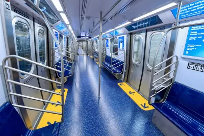 Interior of a subway car with wide doors and blue floors and seats.