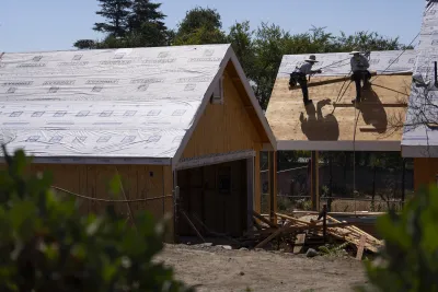 Two workers on roof of house under construction in Altadena, California with other house under construction next to it.
