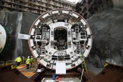 The tunnel-boring machine, a circular drill manned by people in high-vis yellow jackets.