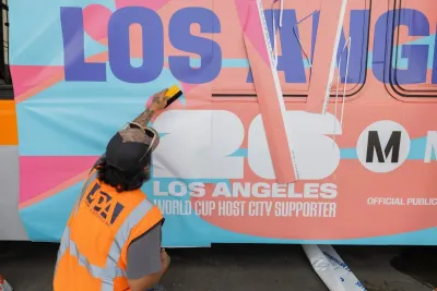 A metro worker wraps an LA Metro bus in wrap celebrating the FIFA World Cup.