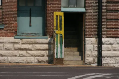 Open door leading to stairway in urban brick building.
