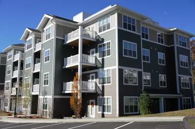 Four-story gray apartment building in suburban area