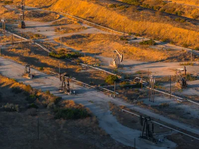 Aerial view of oil field in California with pumpjacks at sunset.