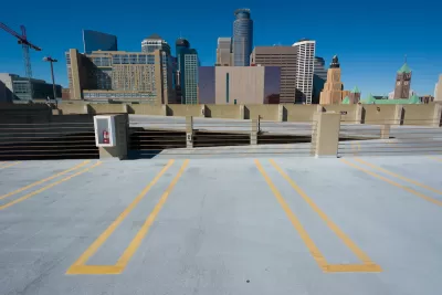 Empty parking spots on top floor of multistory garage with Minneapolis skyline in background.