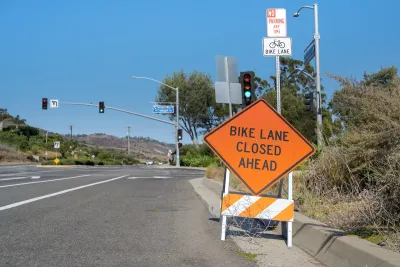 Orange "Bike Lane Closed Ahead" sign on a-frame in roadway.