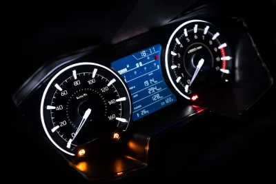 Close-up on car dashboard with odometer and speedometer at night.