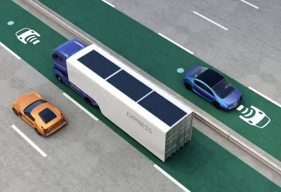 Rendering of truck and cars driving on green electric vehicle charging roadway lane.