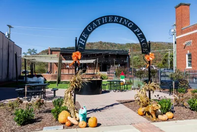 Public space with seating and 'The Gathering Place' metal sign on gateway arch in Erwin, TN.