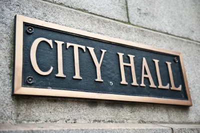 Close-up of "City Hall" plaque on building with gold lettering on black.