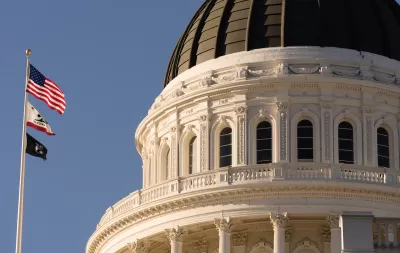 Close-up of Californis state capitol dome with U.S., California, and POW/MIA flags on flagpole.