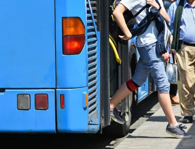Passengers exiting the back door of a blue public bus.