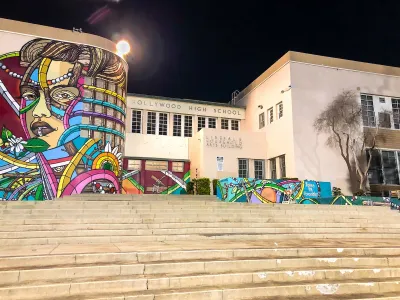 Colorful murals on exterior of Hollywood High School in Los Angeles, California against night sky.