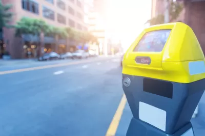 Close-up of yellow and grey smart parking meter with blurred city street in background.