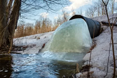 Culvert under a road in northern Wisconsin with frozen water blocking most of the pipe.
