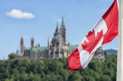 Close-up on Canadian flag with Canada Parliament building blurred in background.