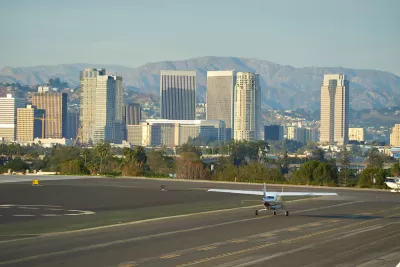 Small plane on runway at Santa Monica airport with high-rise buildings in background.