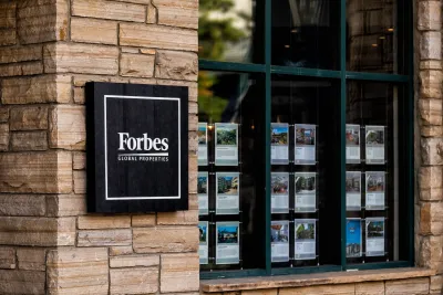 Real estate listings in window of Forbes Properties office.