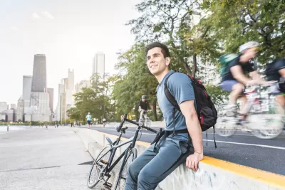 Man sitting on concrete wall with bike next to bike lane on Chicago waterfront.