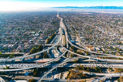 Aerial view of freeway interchange in Los Angeles with low-rise housing on either side and mountains in the background