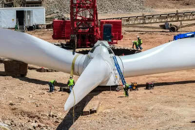 White wind turbine sitting on ground at wind farm construction site.