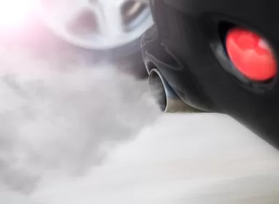 Close-up of car tailpipe with smoke coming out.