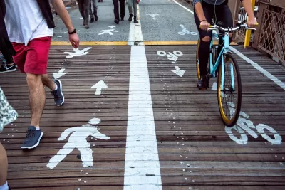 Close-up on wooden section of bike and pedestrian path marked with ped symbols on one side and bike symbols on the other.