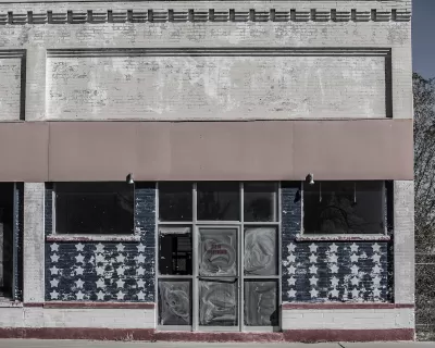 Faded image of vacant storefront in rural area with American flag stars painteind on windows.