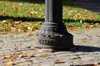 CLose-up of bottom of lamp post with NY CITY plaque on cobblestone sidewalk in Central Park, New York City.